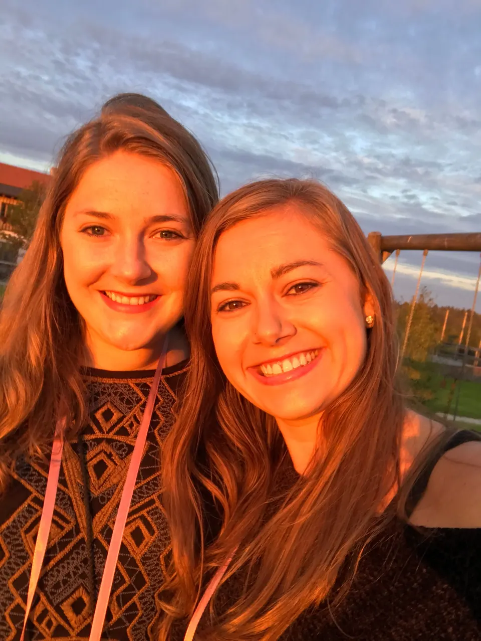 Molly and a friend smiling in golden-hour light