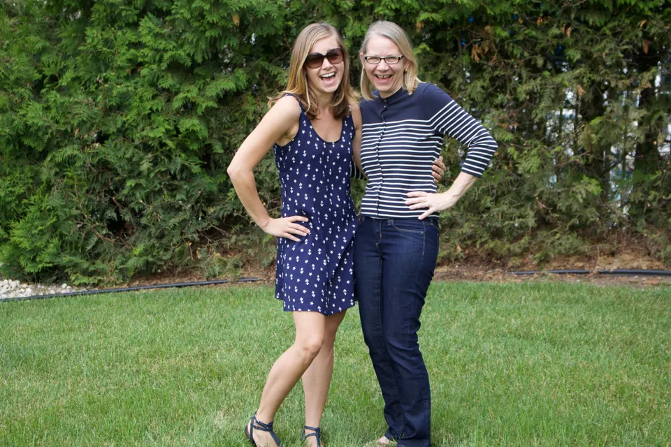 Molly and a friend posing together on a lawn in front of a hedge