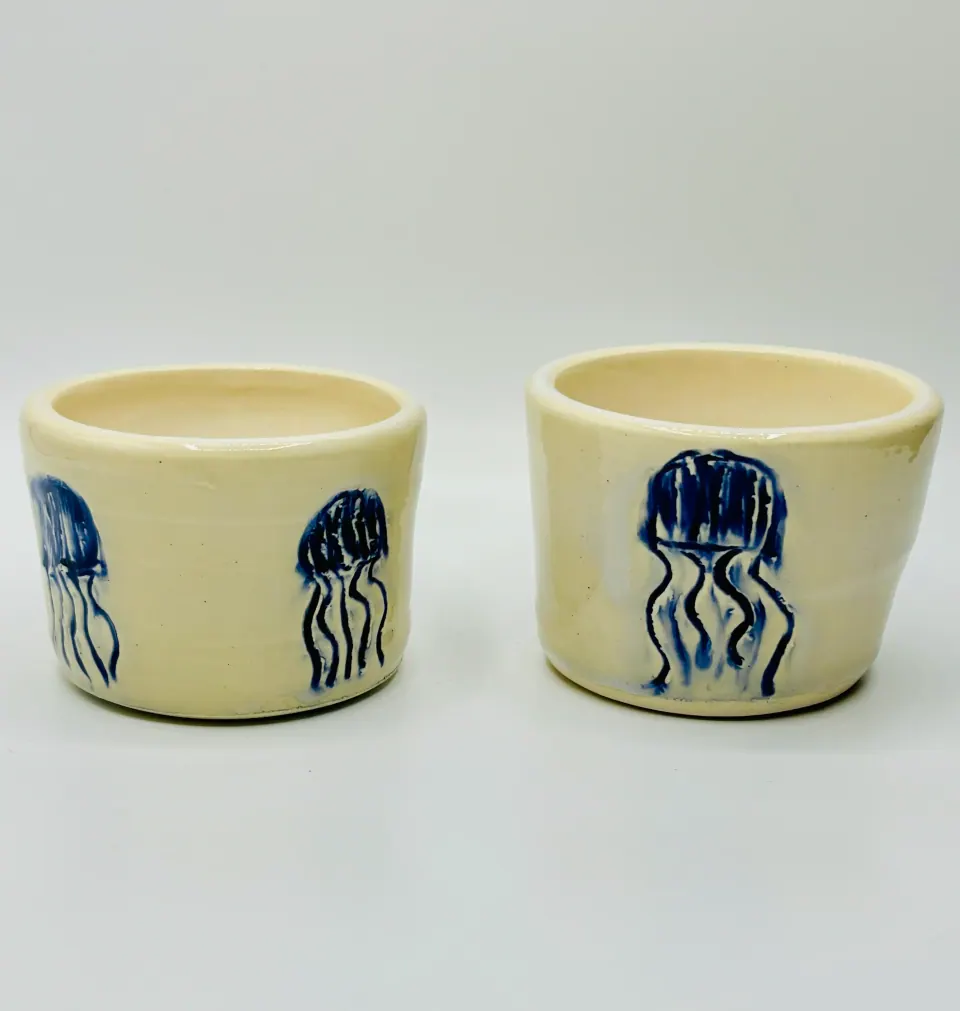 Two small cream ceramic cups with carved jellyfish painted in cobalt blue