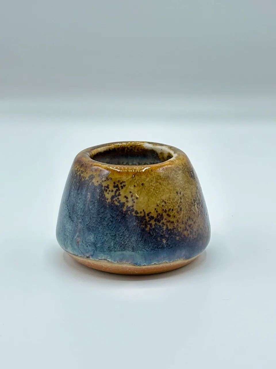 Small tapered ceramic pot with a narrow mouth, glazed in speckled amber over deep blue