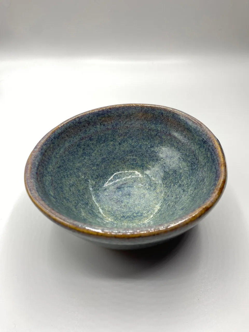 Wide ceramic bowl with a mottled pale blue-green glaze and a warm brown rim
