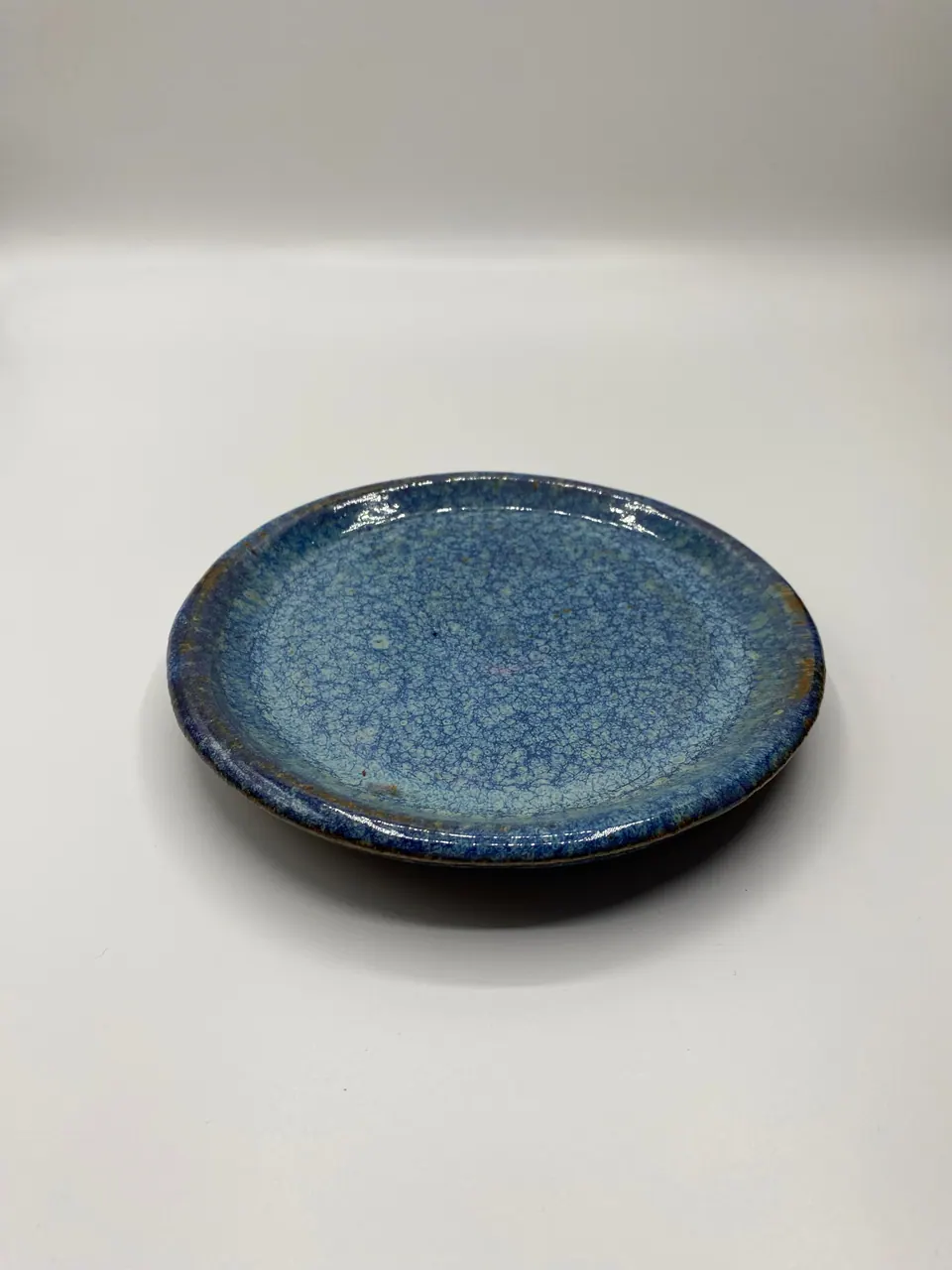 Small ceramic plate with a speckled sky blue glaze and a darker blue rim