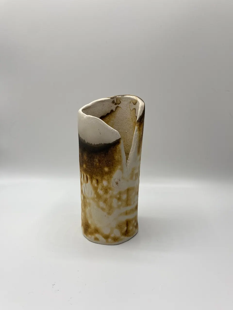 Tall slender white ceramic vase with a folded lip and smoky brown and black fire markings
